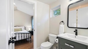 Une chambre avec un lit, une salle de bain avec des toilettes, un lavabo et un miroir.