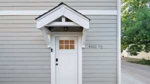 Une porte blanche avec une petite fenêtre, une boîte aux lettres et le numéro de maison 4442.