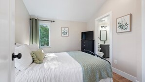 Une chambre à coucher avec un lit, une fenêtre, un téléviseur, une commode et un miroir.