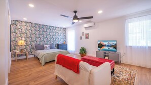 A modern bedroom with a bed, a sofa, a TV, and a ceiling fan. - Facing Collins Garden Park, 2nd Floor Studio (San Antonio)