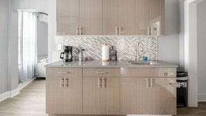 Eine moderne Küche mit hellen Holzschränken, einer gefliesten Spritzschutzwand und einem Edelstahlspülbecken.