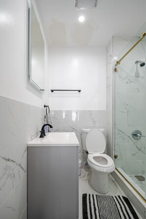 Un baño moderno con lavamanos, inodoro y cabina de ducha de vidrio.