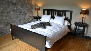 Una cama con cabecera oscura, ropa de cama blanca y dos mesitas de noche con lámparas.