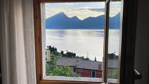 A room with a large window overlooking a lake and mountains. - Casa Oliva Castelletto sul Garda - Natura Pura in Vista Lago (Brenzone sul Garda)