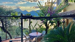 A terrace with a table and chairs, overlooking a body of water and mountains. - Casa Oliva Castelletto sul Garda - Natura Pura in Vista Lago (Brenzone sul Garda)