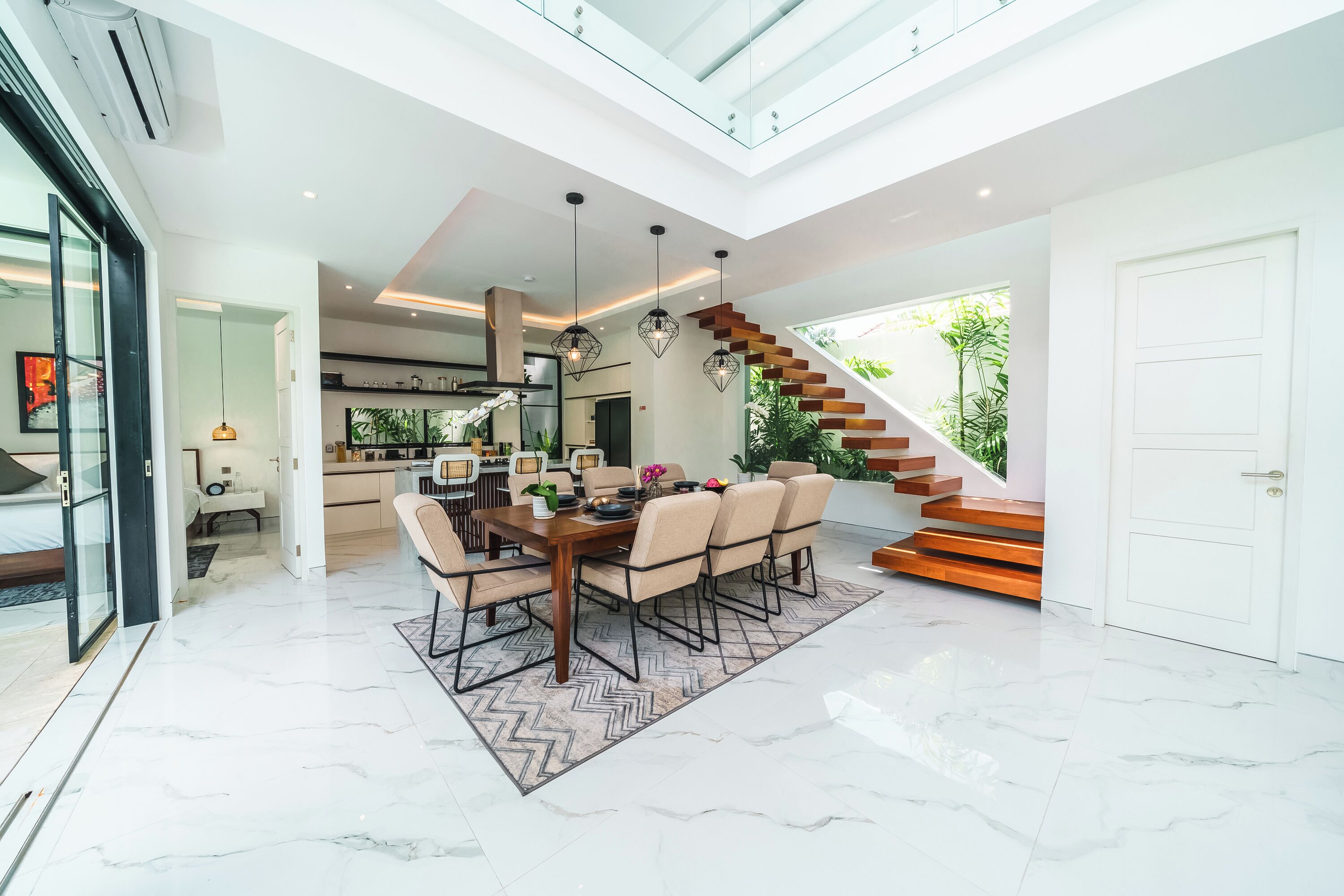 Un interior modern amb zona de menjador, cuina i escala.