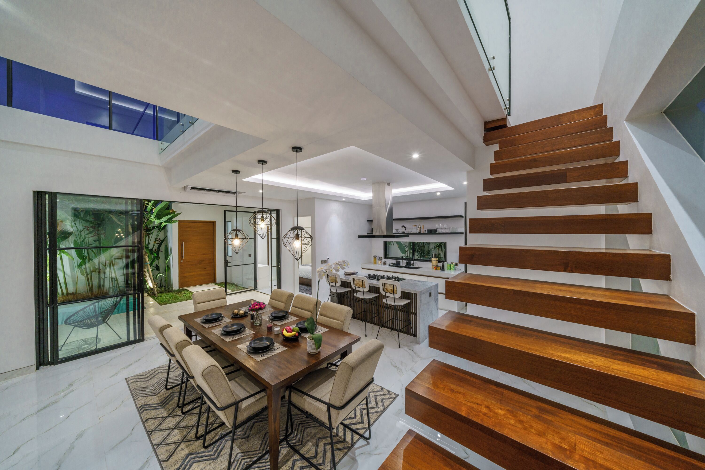 Ein modernes Interieur mit Essbereich, Küche und einer Holztreppe.