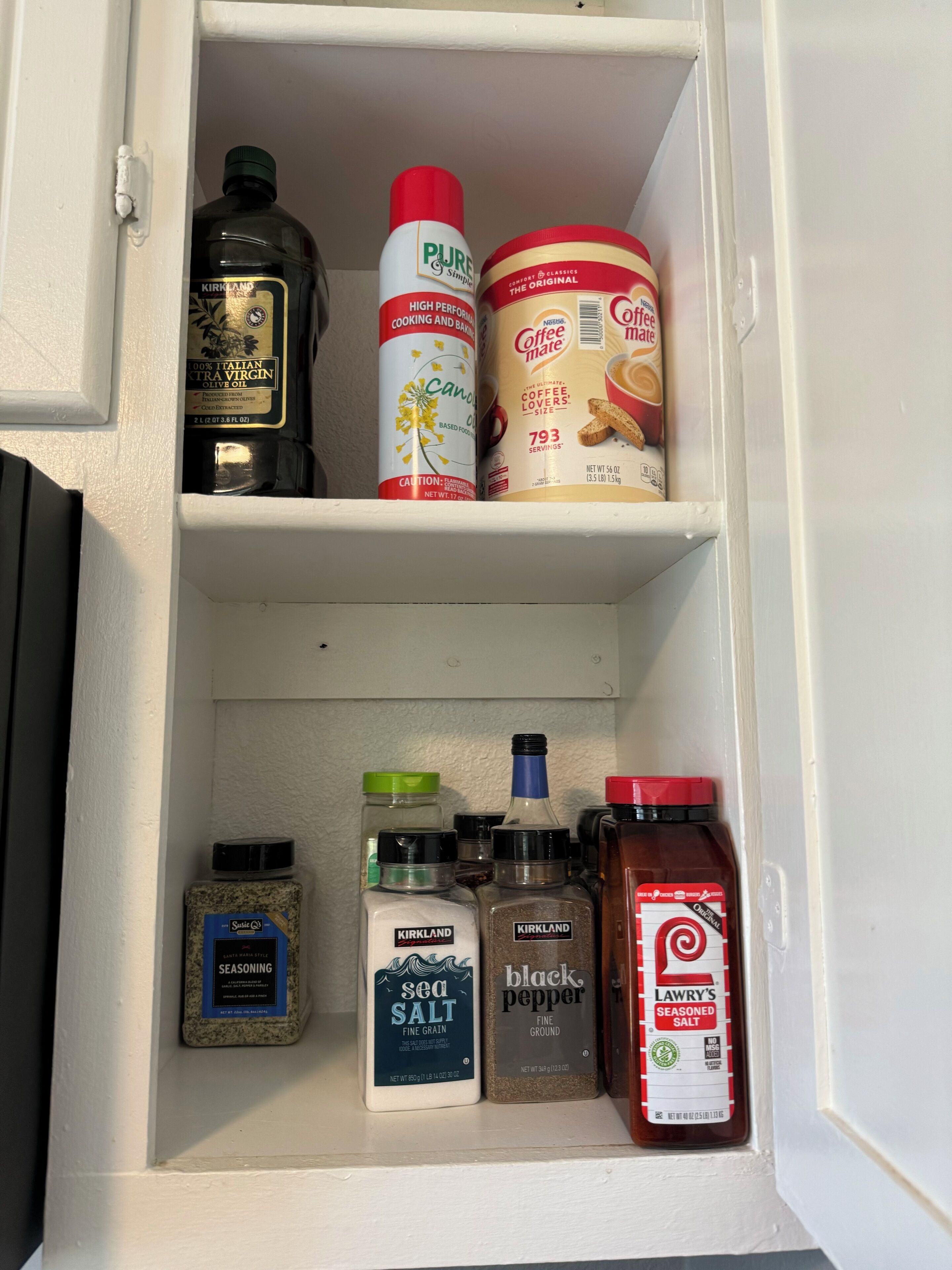 A kitchen pantry with various food items including olive oil, coffee, sea salt, and black pepper.