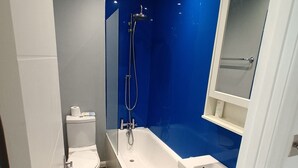 A modern bathroom with a toilet, bathtub, and a shower.
