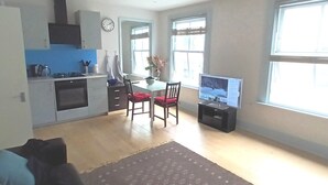 A compact living space with a kitchenette, dining area, and a TV.