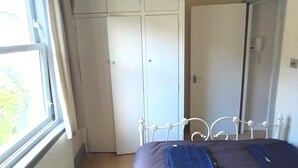 A bedroom with a bed, a wardrobe, and a window.