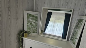 Een hoekappartement met een witte dressoir, kunstwerken in lijsten en een potplant.