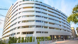 Un hôtel à plusieurs étages, doté d’une façade incurvée, de balcons et d’une entrée fermée par un portail.