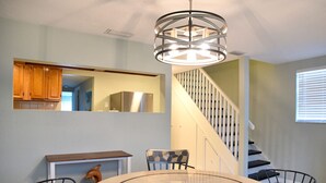 Un espace repas comprenant une table ronde, des chaises, un lustre et un escalier.