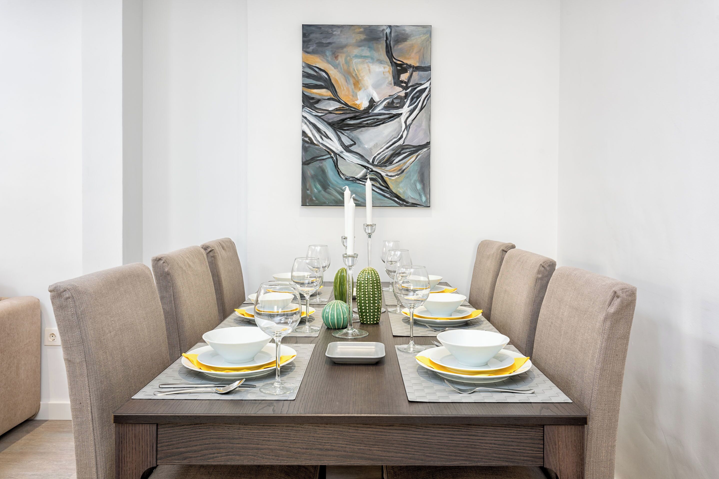 Mesa de comedor para seis personas con un cuadro abstracto moderno en la parte superior.