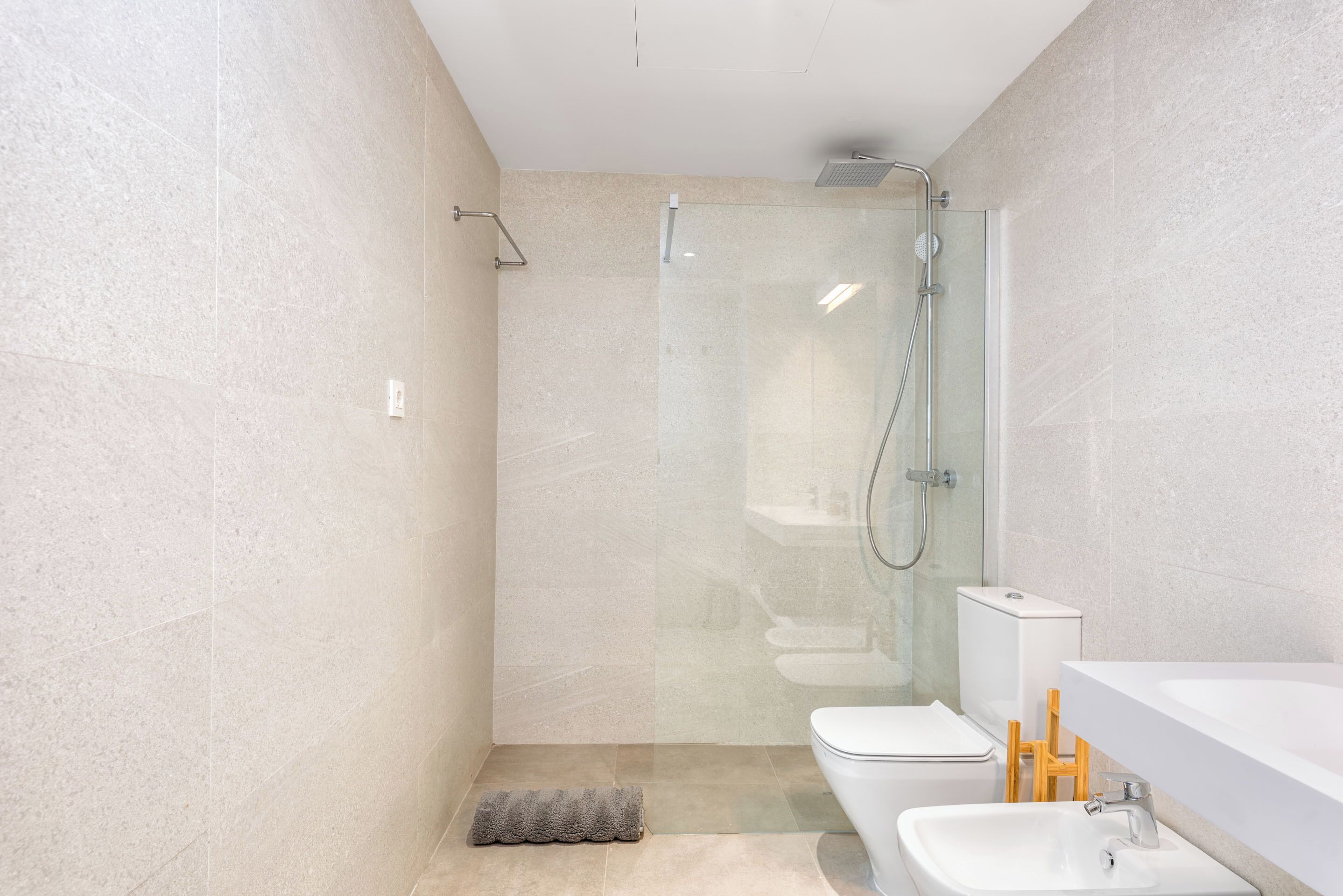Ein modernes Badezimmer mit einer gläsernen Duschkabine, einer weißen Toilette und einem Waschbecken mit Waschtisch.