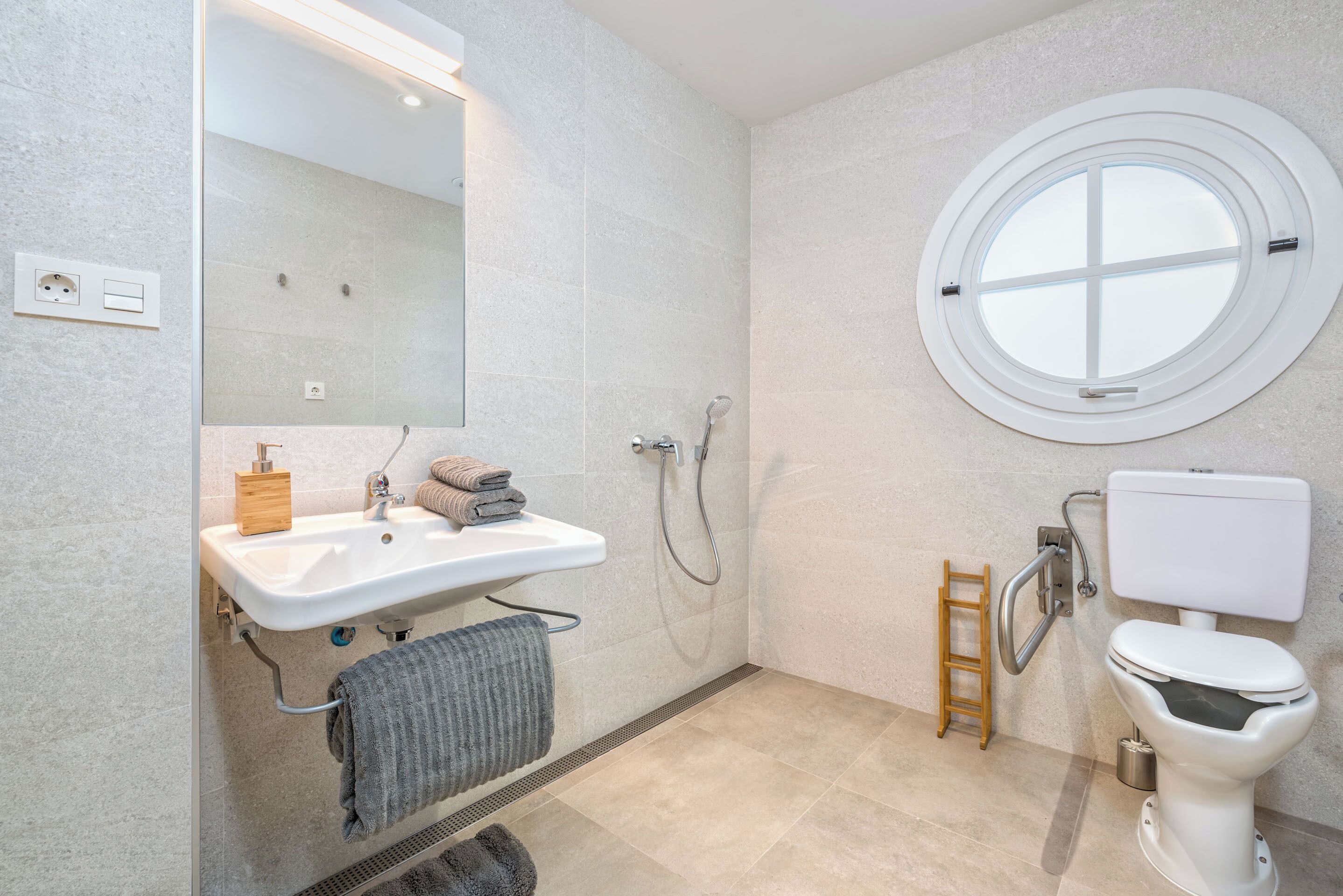 A modern bathroom with a sink, mirror, toilet, and shower.