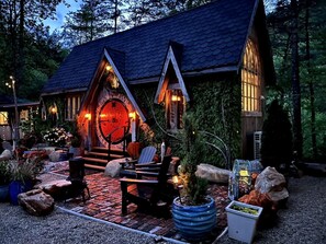 Una cabaña con una puerta de madera grande, asientos exteriores y una chimenea de piedra.