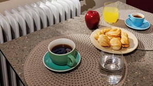 A breakfast table with a view of the sea, a radiator, and potted plants. - Jolly Suites (Heraklion)
