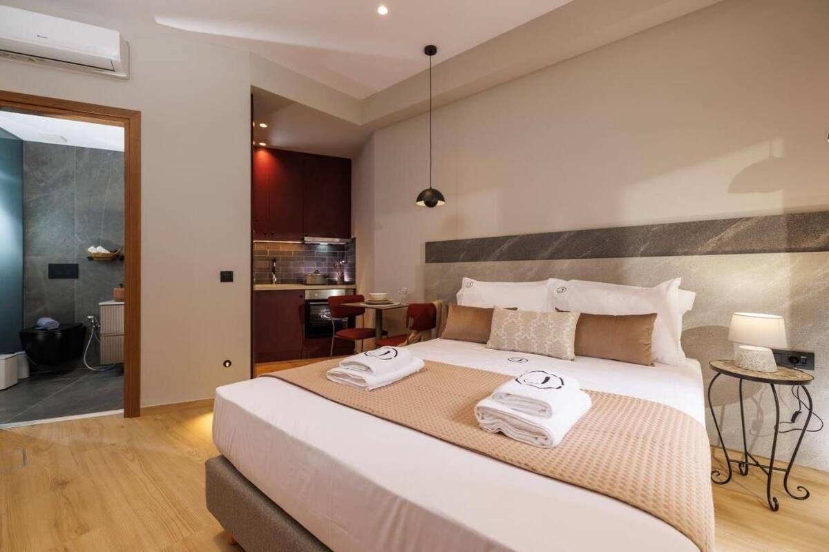 Ein modernes Hotelzimmer mit einem großen Bett, einer kleinen Küchenzeile und einer separaten Sitzecke.