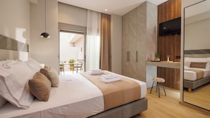 A modern hotel room with a large bed, a small stool, a TV mounted on the wall, and a mirror reflecting the room. - Jolly Suites (Heraklion)