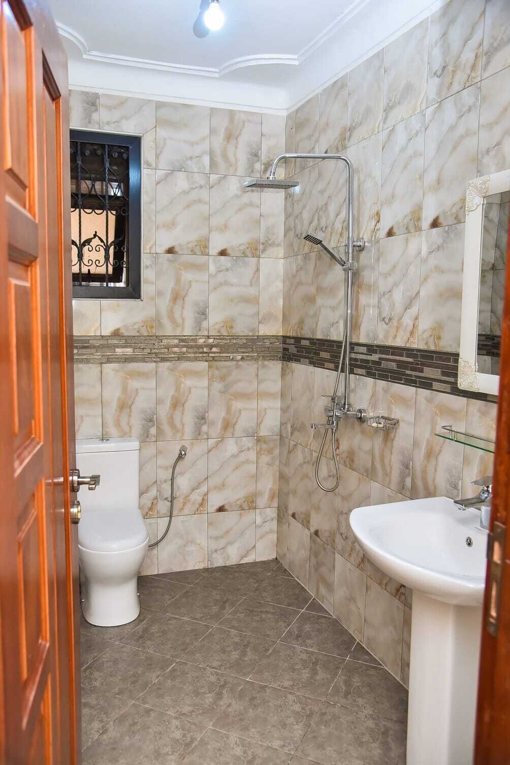 A bathroom with a toilet, a shower, and a sink.