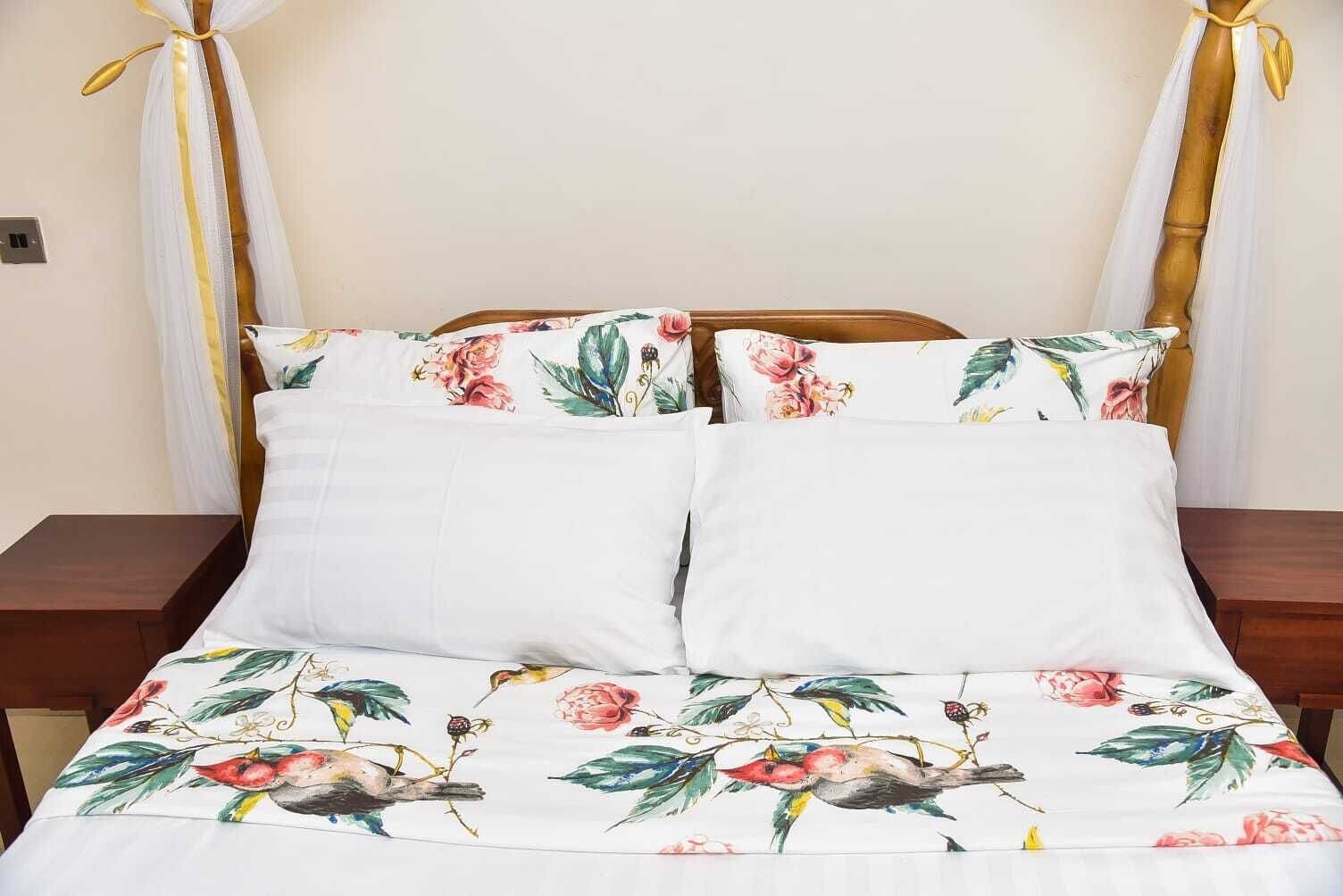 A bed with floral bedding and two pillows, wooden headboard, and two nightstands.