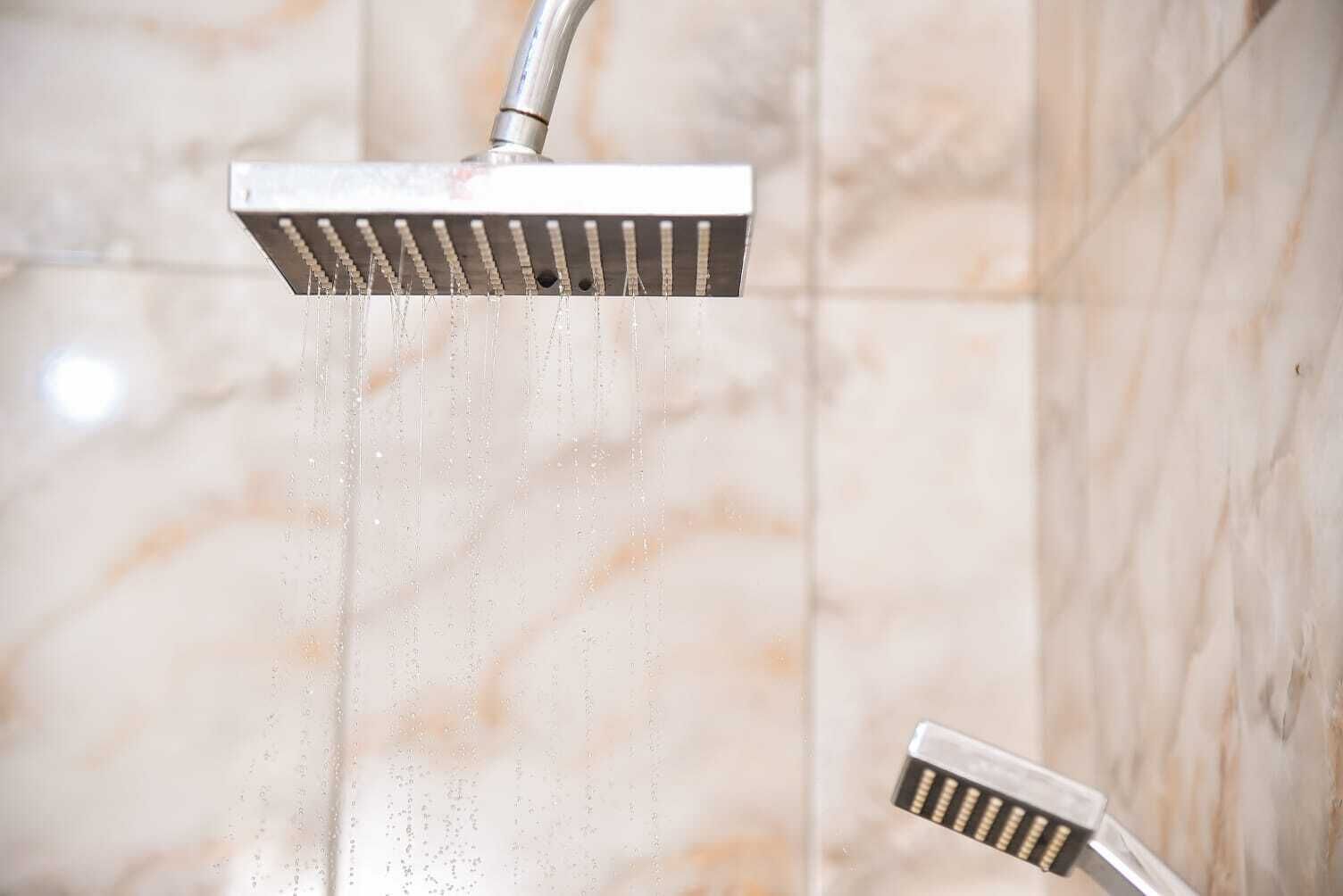 A showerhead with water running, mounted on a wall with a marble-like texture.