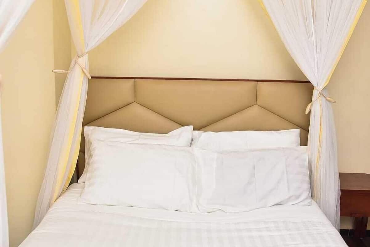 A bed with white linens and a canopy.