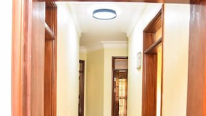 A hallway with wooden doors and a tiled floor. - KCube Villas Kampala (Kampala)