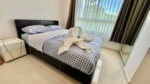 A neatly made bed with checkered bedding and a decorative swan pillow arrangement. - 2-bedroom condo in delightful Muang Pattaya with AC, WiFi, fitness room (Muang Pattaya)