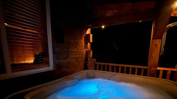 Un bain à remous doté d’un panneau de commande numérique, de parois en bois et d’une fenêtre avec stores.