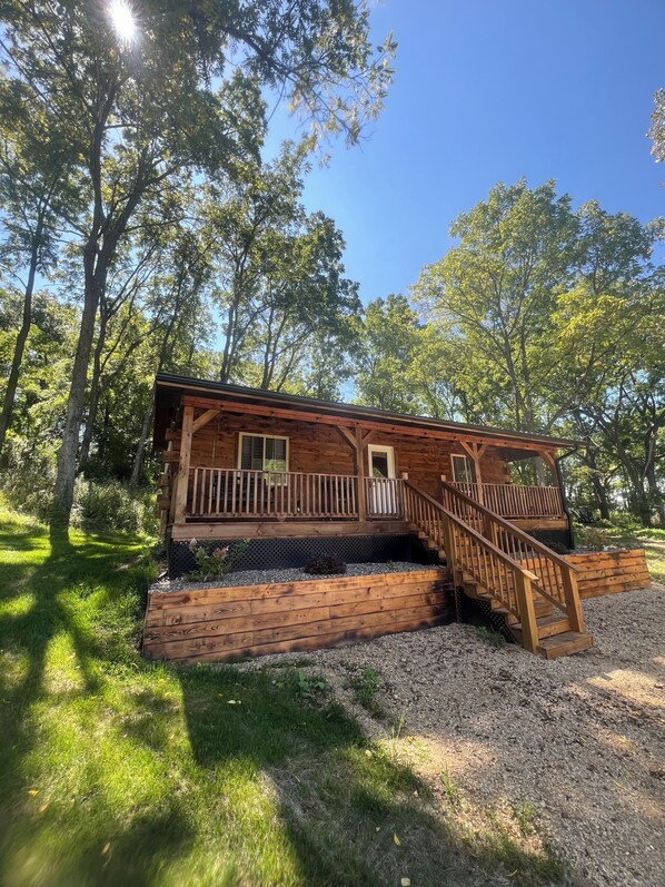 Une cabane en bois dotée d’une terrasse en bois et d’un escalier menant à un porche abrité.