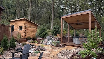 Una cabaña de madera con terraza, un patio cubierto con jacuzzi y un sendero de piedra.