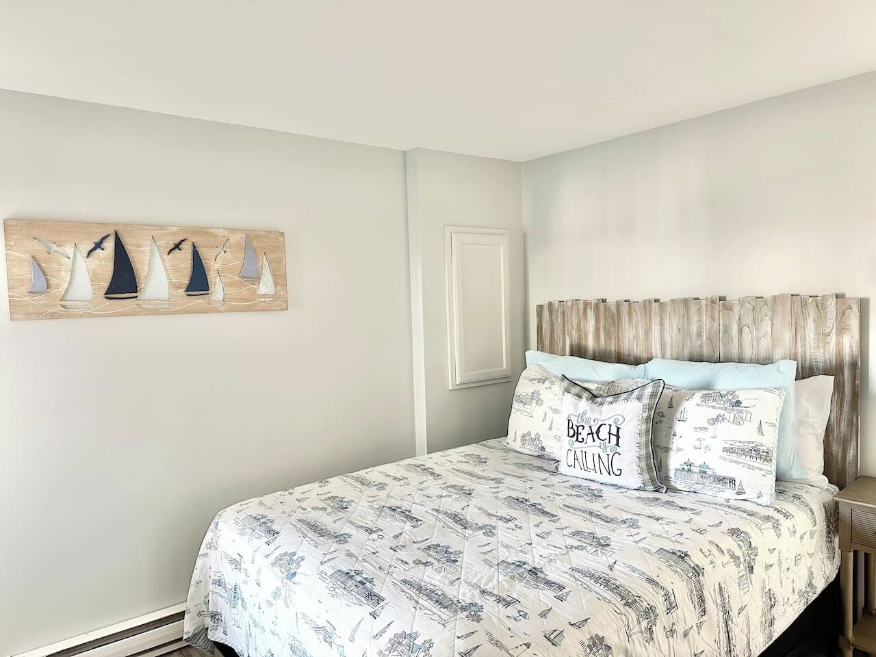 A bedroom with a bed, a headboard, a nightstand, and a wall art piece.