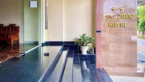 Ein Hotel Eingang mit Glastür, einer Rezeption und einem Schild mit der Aufschrift 'DMC PHUC HOTEL'.