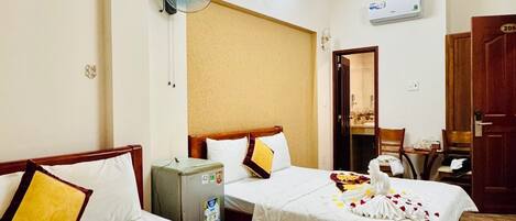 Habitación de hotel con dos camas, un minibar, un equipo de aire acondicionado y una puerta que da al baño.