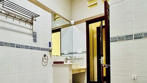 Ein Badezimmer mit Toilette, Waschbecken und Spiegel. An der Wand befindet sich ein Handtuchhalter und eine Tür zu einem anderen Raum.