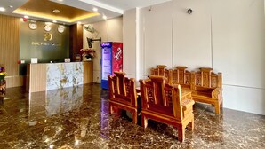 Eine Hotelhalle mit Rezeption, einem Pepsi-Kühlschrank, Holzsesseln und einer Kristallleuchtre.