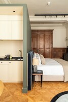 Un dormitorio con una cama, una mesita de noche, una lámpara y un armario de madera.