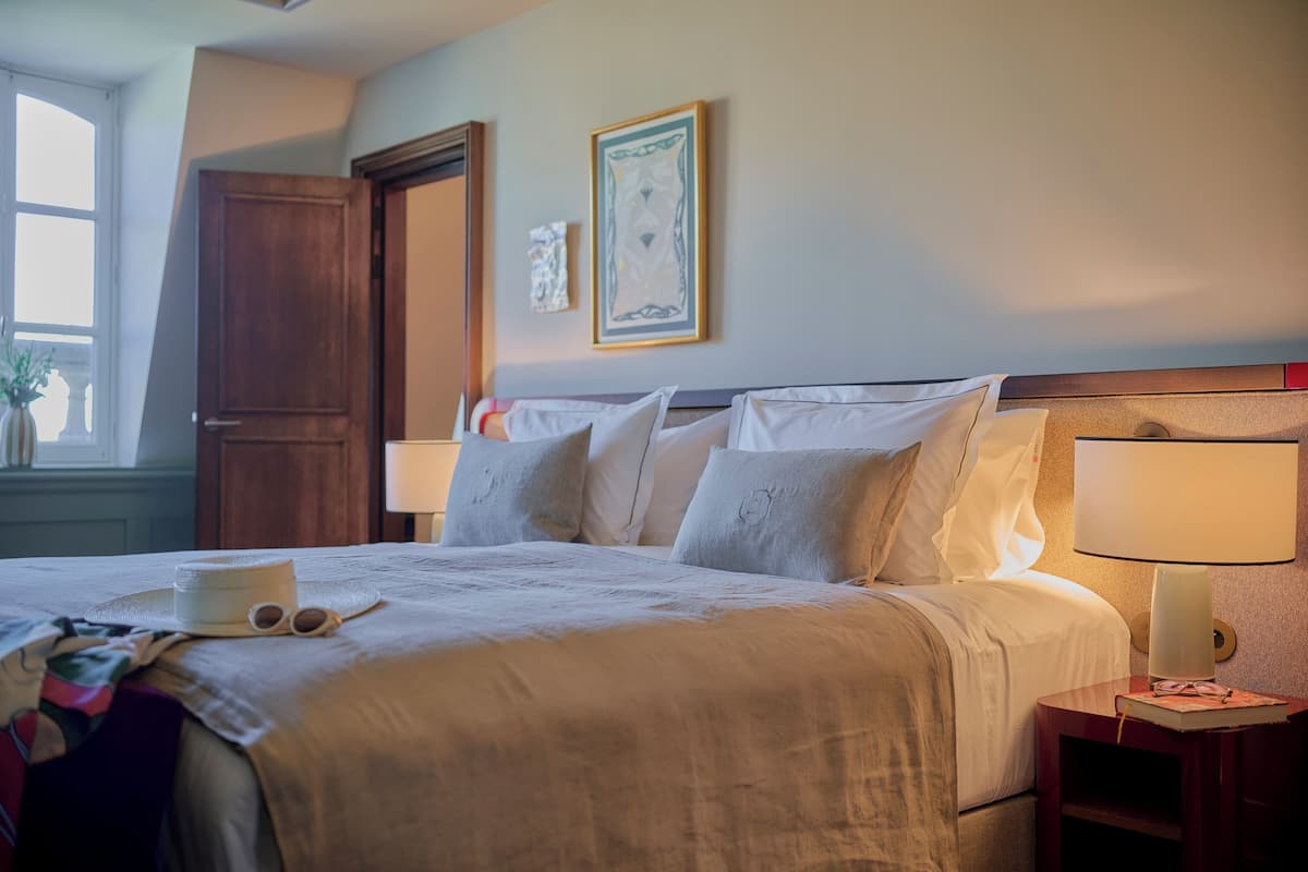 A neatly made bed with pillows and a bedside table with a lamp.