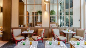 A modern restaurant with high windows, red chairs, and marble tables. - Faubourg 21 – The Leading Hotels of the World (Brussels)