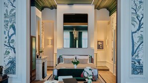 A modern hotel room with a large bed, a desk with a laptop, a vase with flowers, and a fireplace. - Faubourg 21 – The Leading Hotels of the World (Brussels)