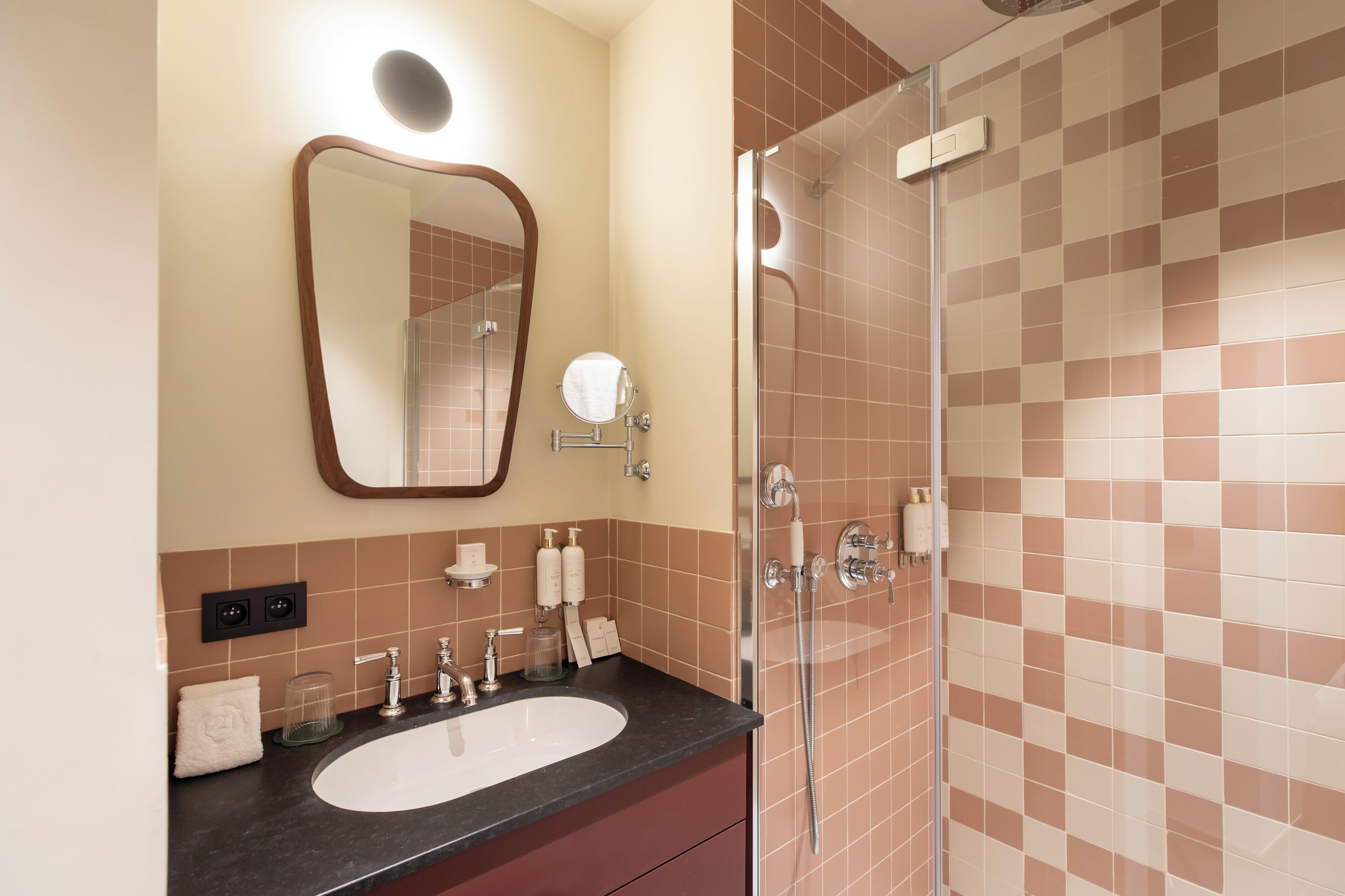 A bathroom with a sink, mirror, and shower.