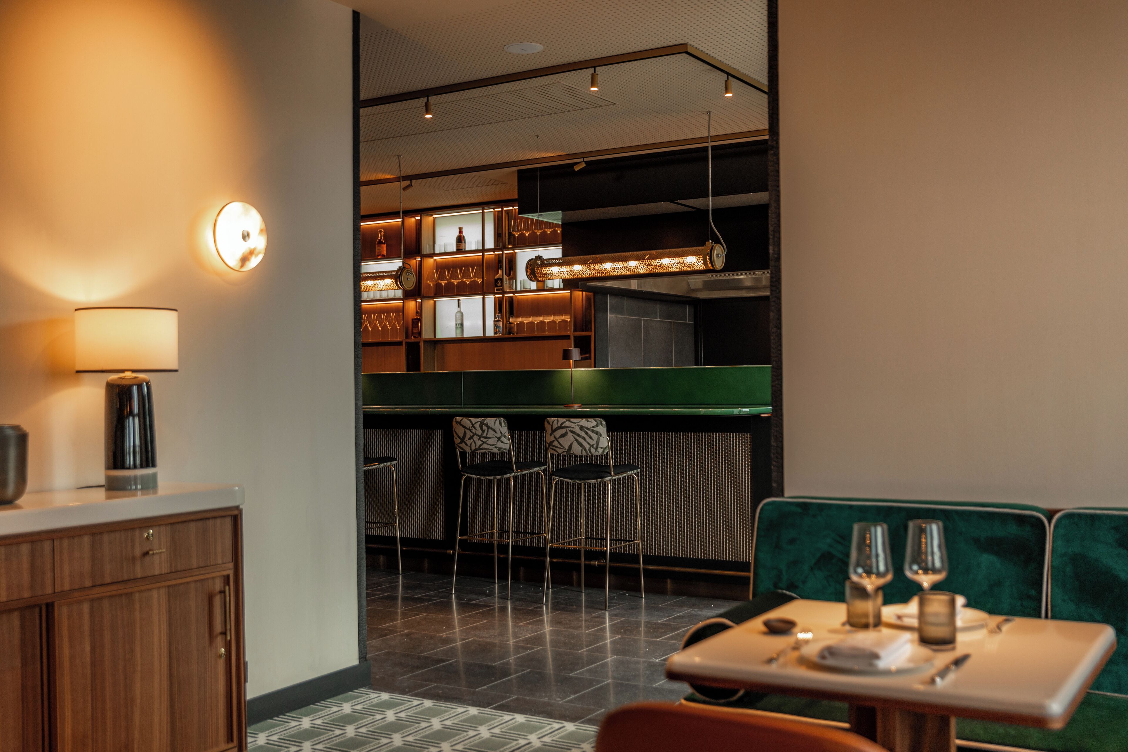 Un restaurante moderno con área de bar, asientos y una cocina a la vista.