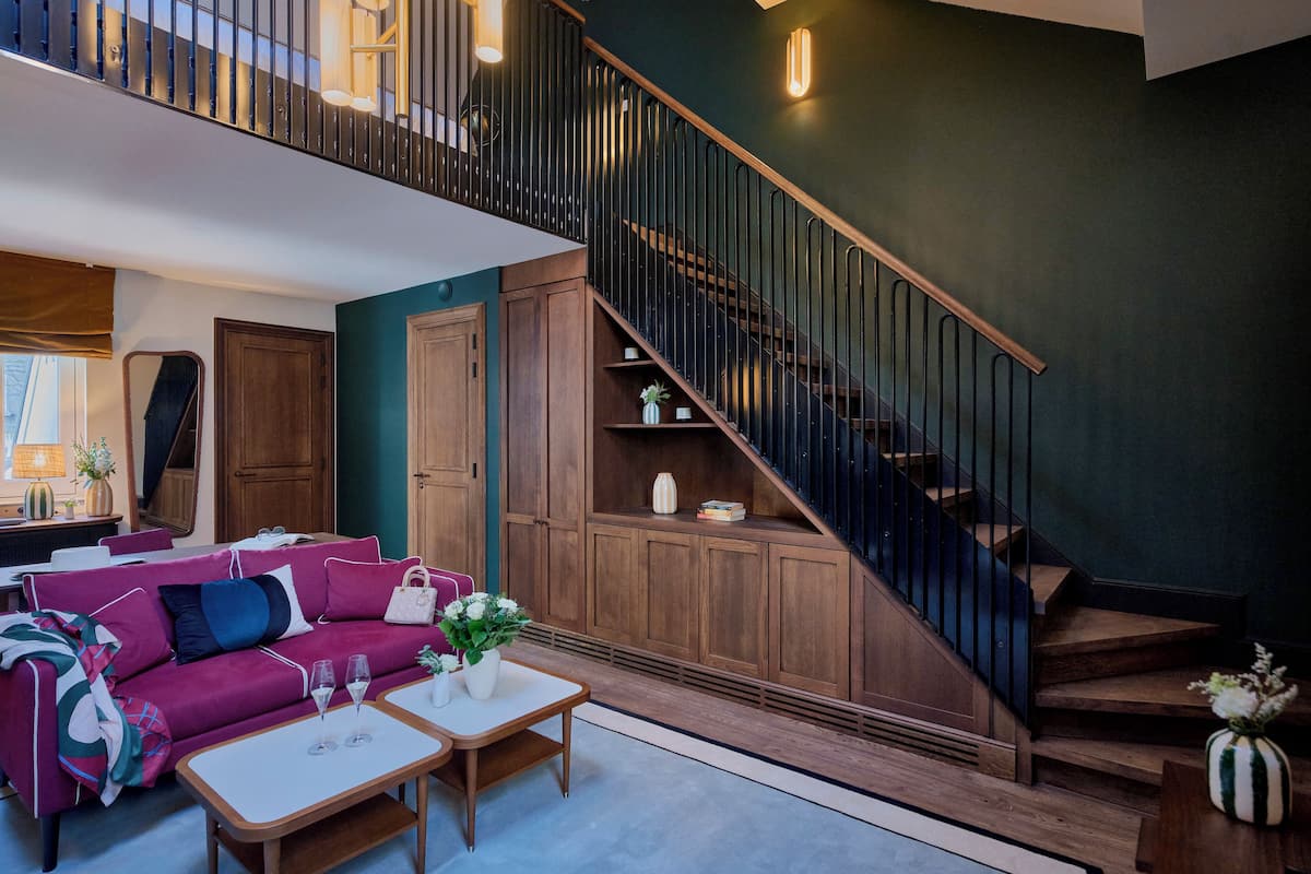 A modern living room with a staircase, wooden furniture, and a view of the upper floor.
