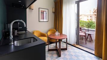 Une cuisine compacte dotée d’un évier et d’un robinet modernes, d’une petite table ronde avec deux chaises, et d’une vue sur un balcon aménagé avec des sièges d’extérieur.