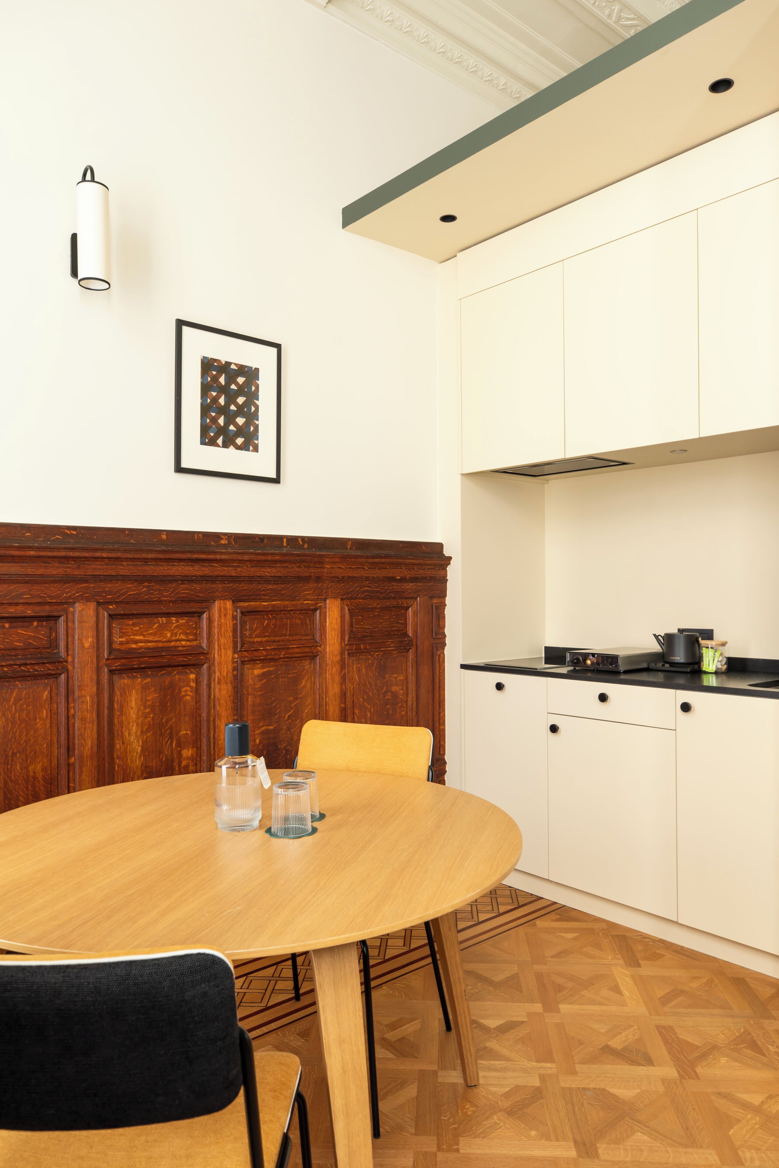 Een eetruimte met een ronde tafel, stoelen en een wand van houten panelen.