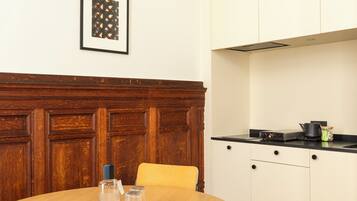 Een eetruimte met een ronde tafel, stoelen en een wand van houten panelen.