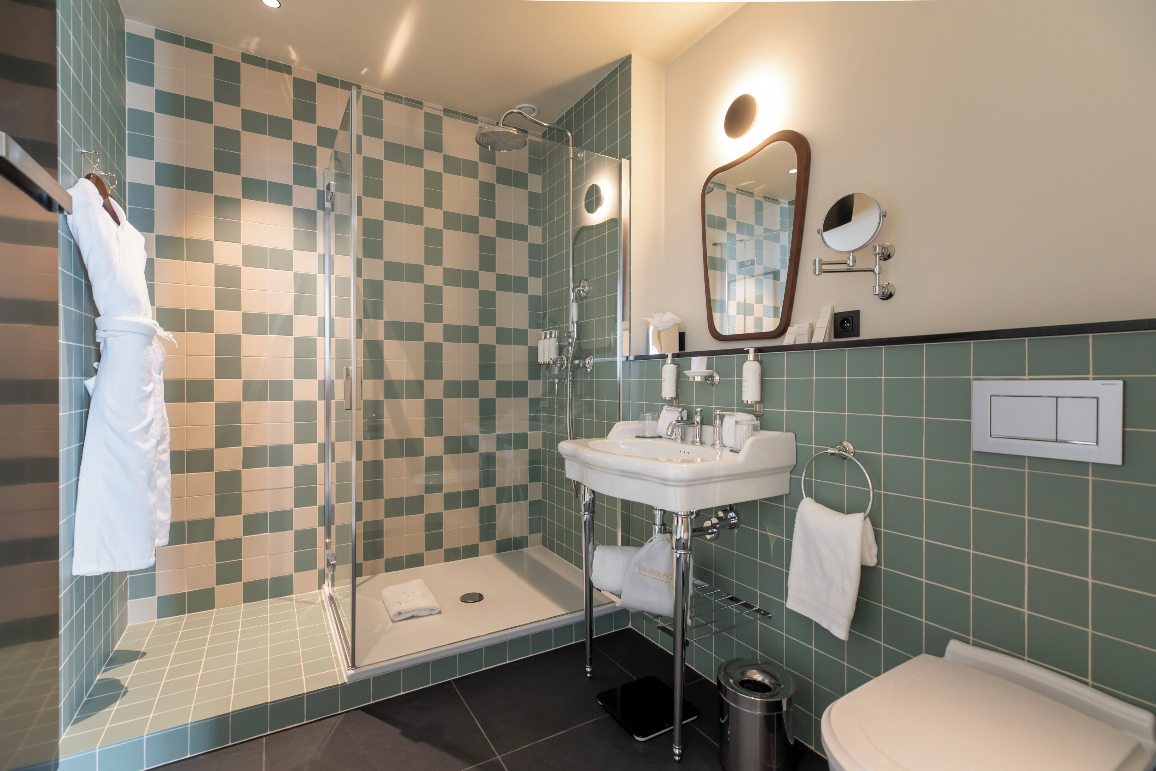 Een badkamer met een douchecabine van glas, een wastafel, een spiegel en een toilet.